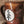Load image into Gallery viewer, Brown ceramic mug with a white circular design featuring black leaf-like patterns on a stone surface.
